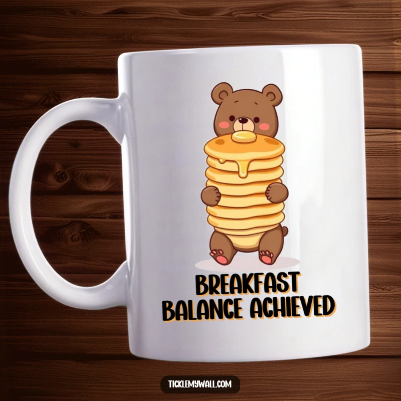 Funny mug depicting a clumsy bear comically attempting to balance a wobbly stack of three pancakes, showcasing breakfast-themed humor.