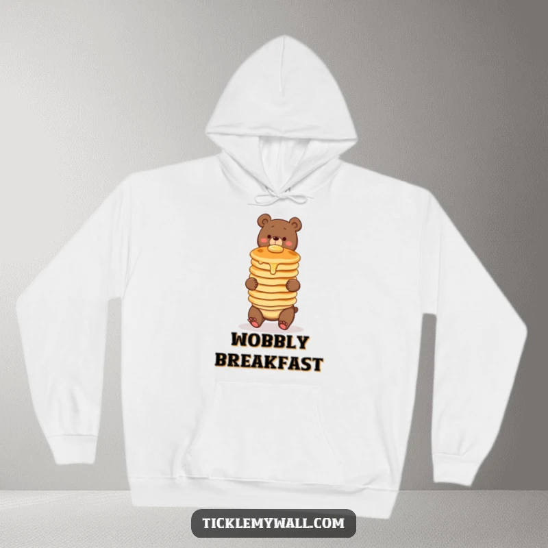Funny hoodie with a clumsy bear character comically balancing a wobbly stack of three pancakes. Cozy and full of breakfast charm.