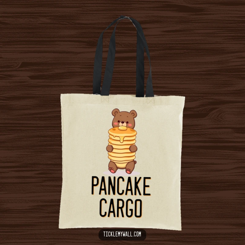 Funny tote bag featuring a clumsy bear comically balancing a wobbly stack of three pancakes. Great for carrying goodies with a smile.